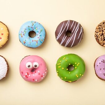 Top view of set of donuts on yellow background. Flat lay, copy space.